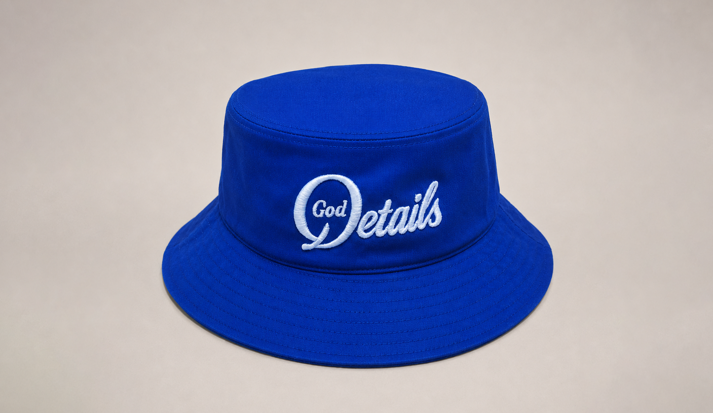 Blue bucket hat with 'God Details' text on a beige background